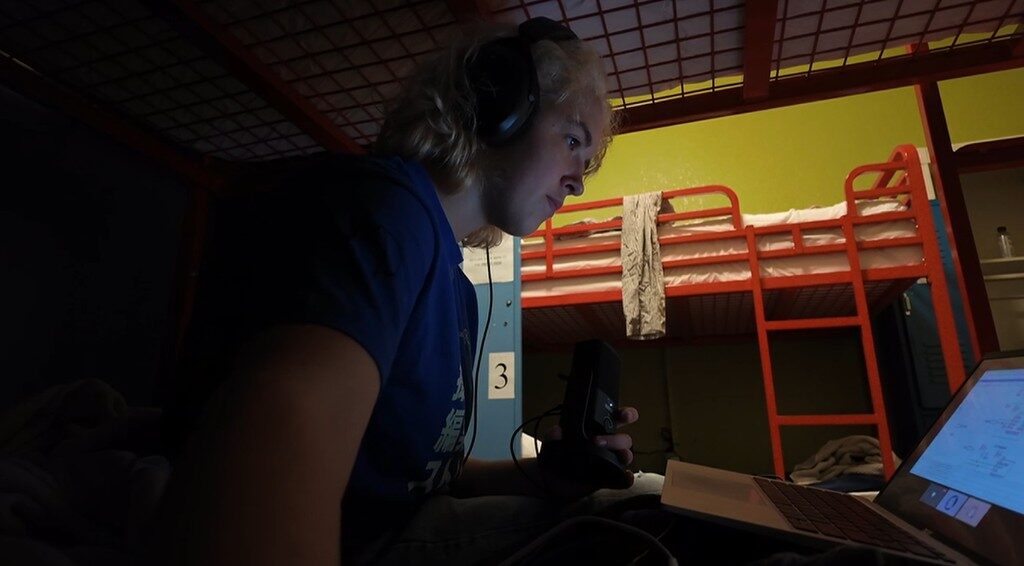 Freesia with headphones, holding a small device next to a laptop