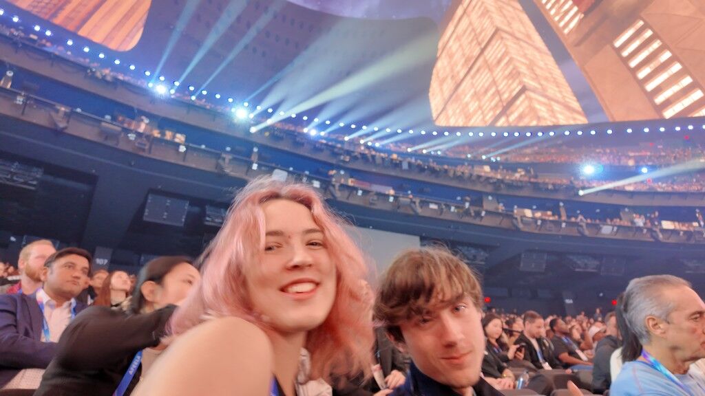 Freesia with pink hair in a huge dark hall, blue spotlights and a lit grid overhead