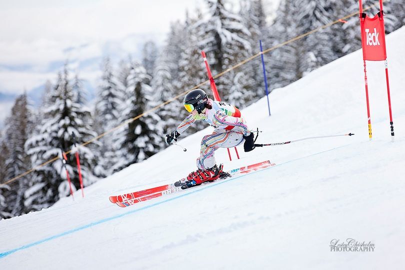 A skier in a patterned suit carving between gates on a snowy slope
