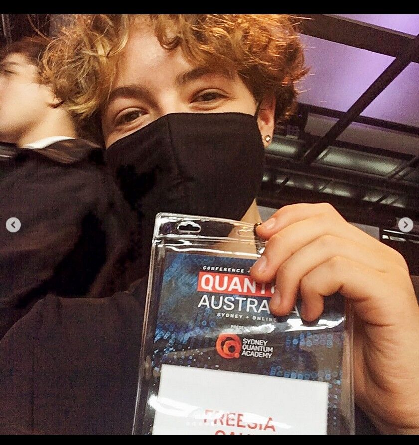 Freesia in a black mask holding a Quantum Australia conference badge