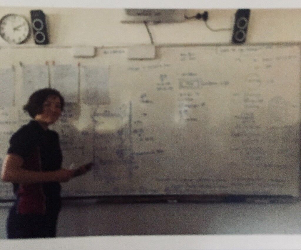 Standing in front of a whiteboard covered in writing