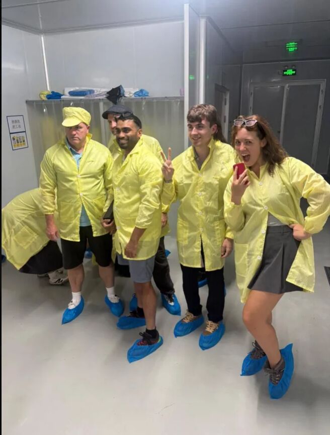 A group in yellow coats and blue shoe covers in a bright corridor