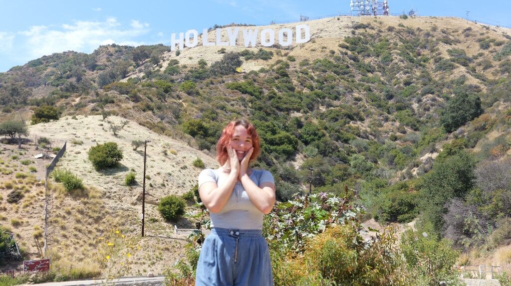 Freesia in front of the Hollywood sign, hands on her cheeks